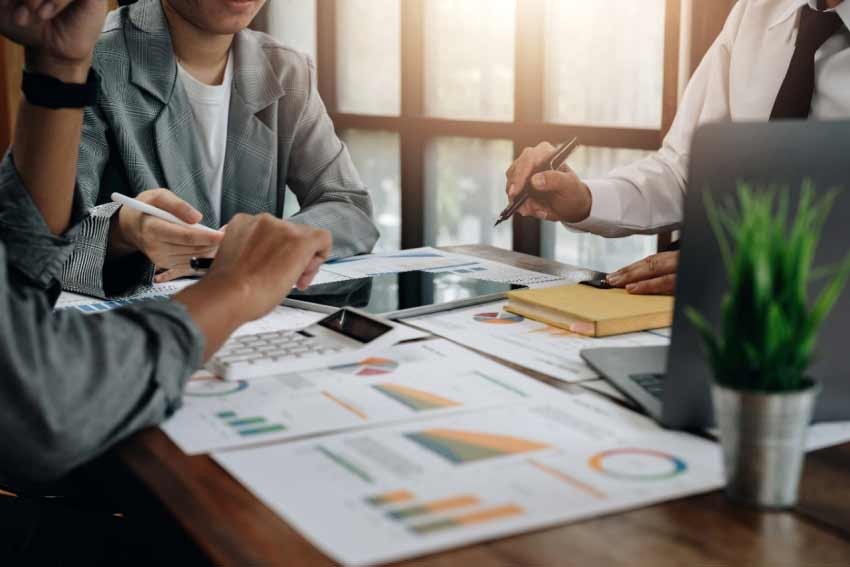 Three colleagues discussing charts over a table - Radio Teleswitch Service (RTS) – what businesses need to know